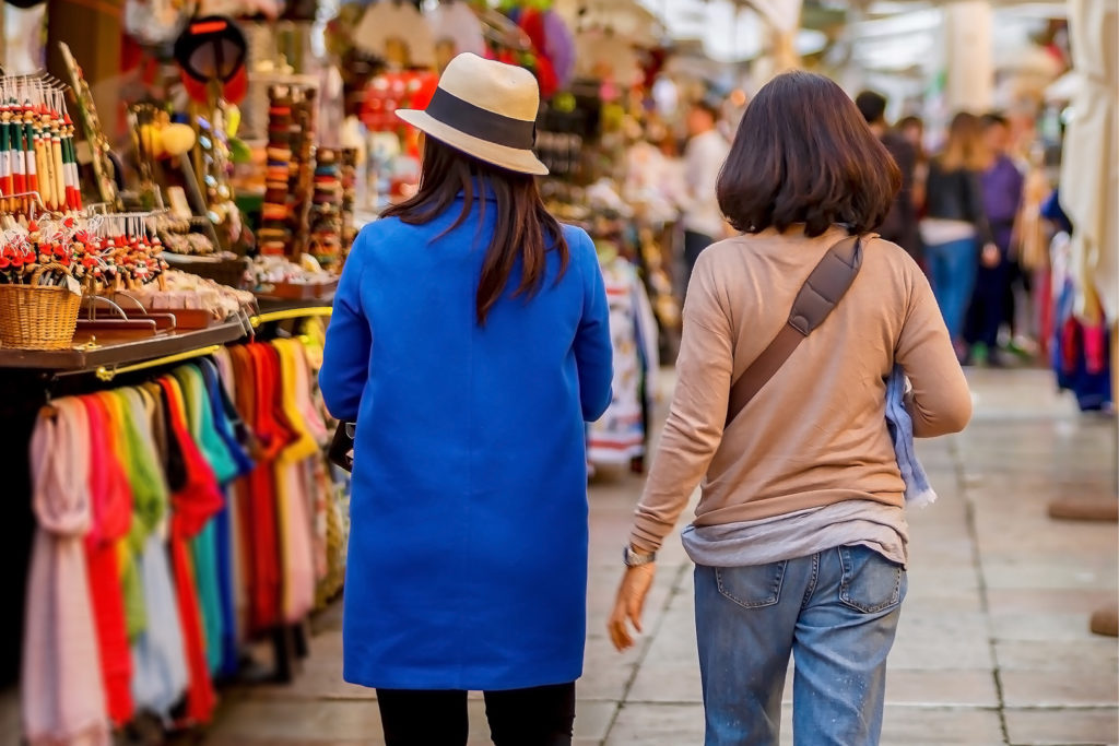 two girls are walking in the shop with a wardrobe